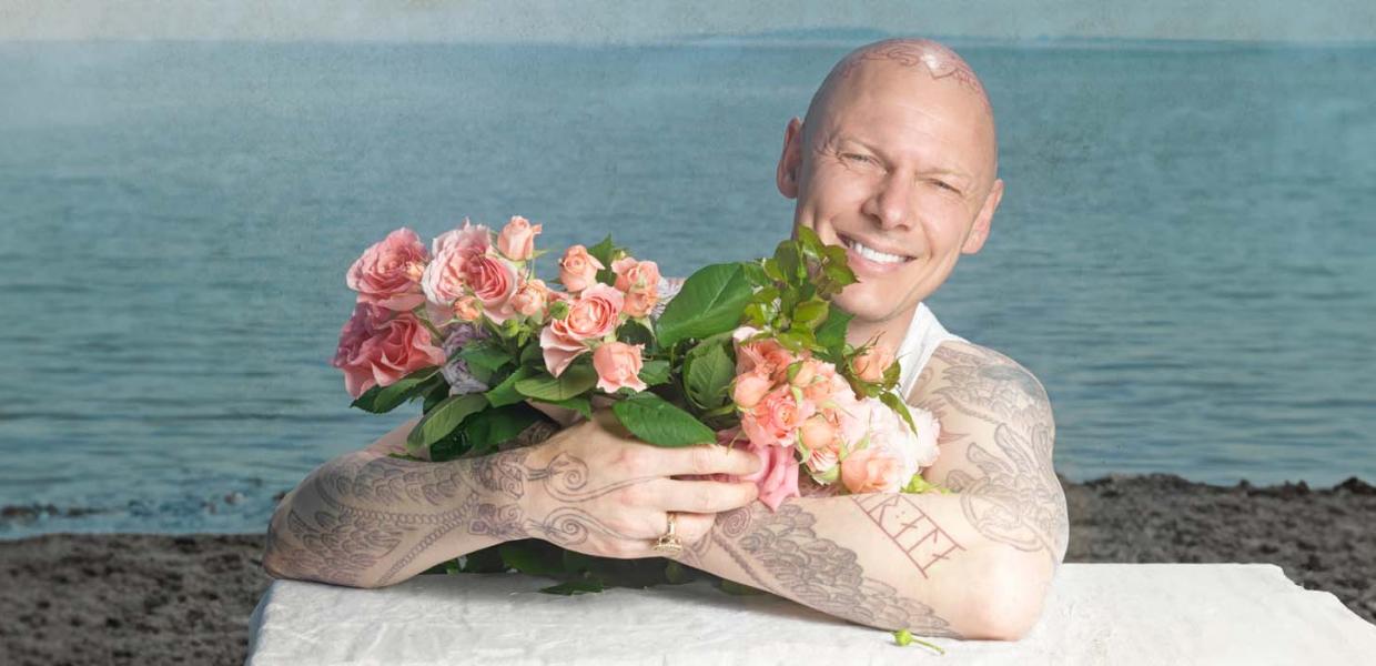 Kunstner Jim Lyngvild på stranden med tatovering og roser