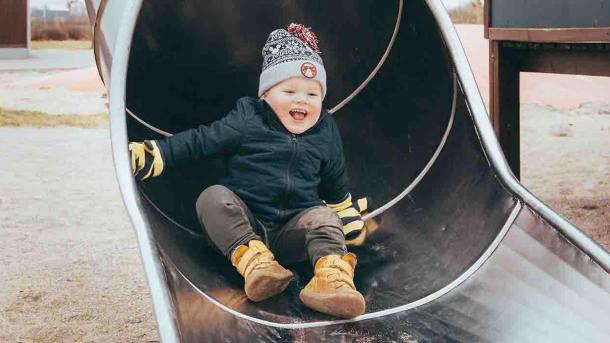 Dreng griner i rutsjebane i vintertid